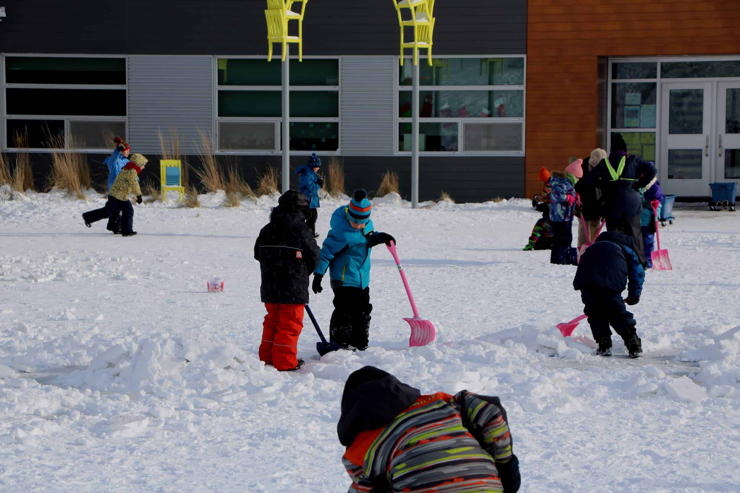 des enfants qui jouent avec des pelles d'hiver dans la cour d'école
